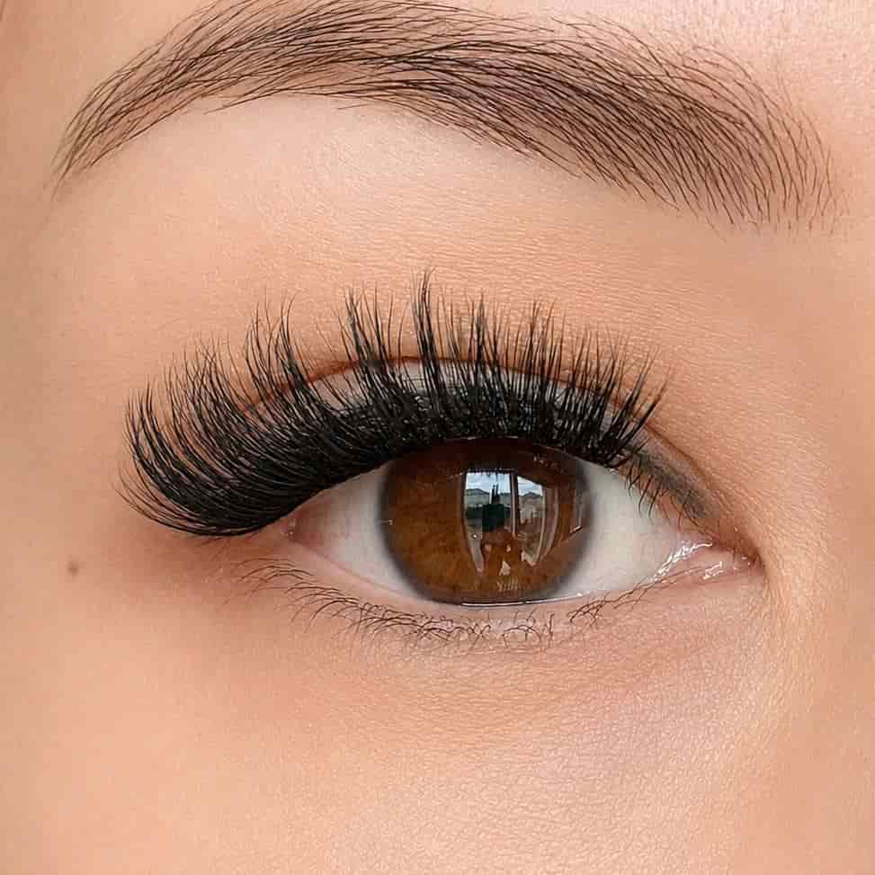 Close-up of an eye with long, dramatic press on lash clusters and a well-groomed eyebrow.