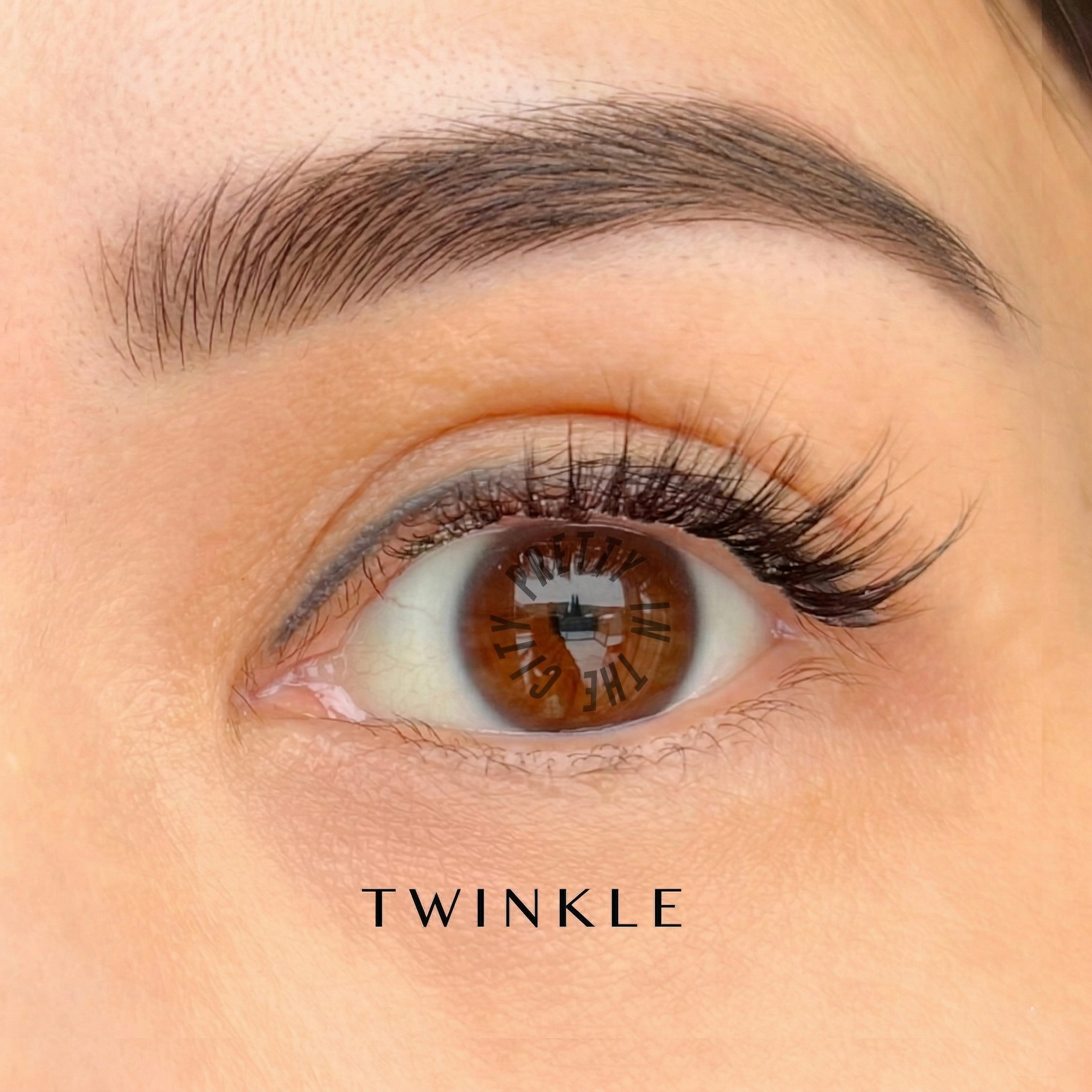 Close-up of an eye with brown irises and natural press on cluster lashes labeled 'TWINKLE'.