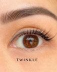 Close-up of an eye with brown irises and natural press on cluster lashes labeled 'TWINKLE'.